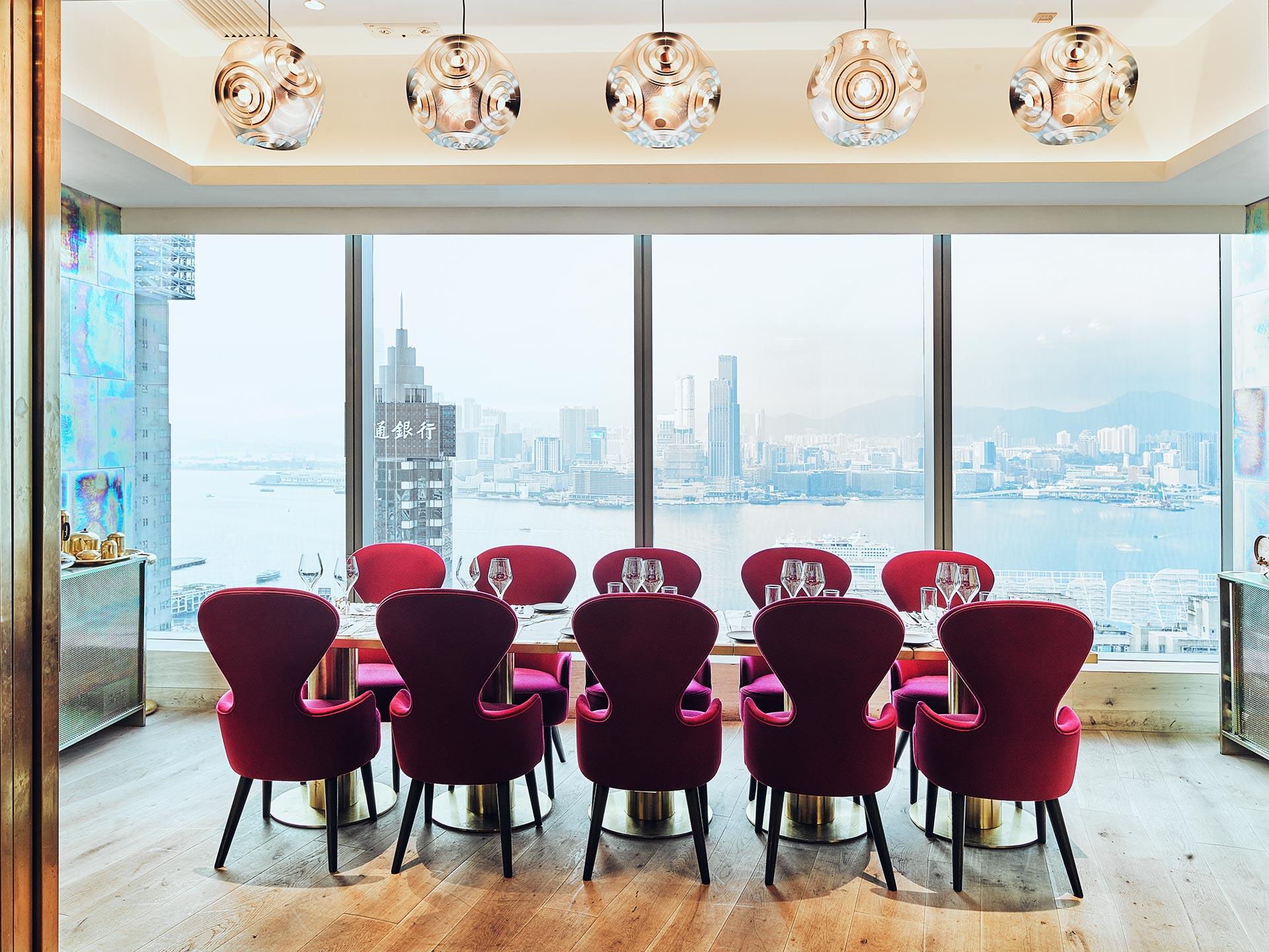 Elegant dining room with red velvet chairs and panoramic city skyline view