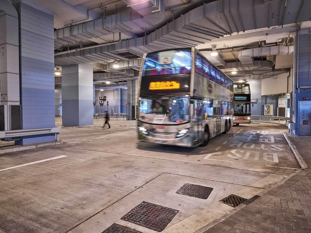 Blue double-decker bus parked inside underground terminal with concrete ceiling