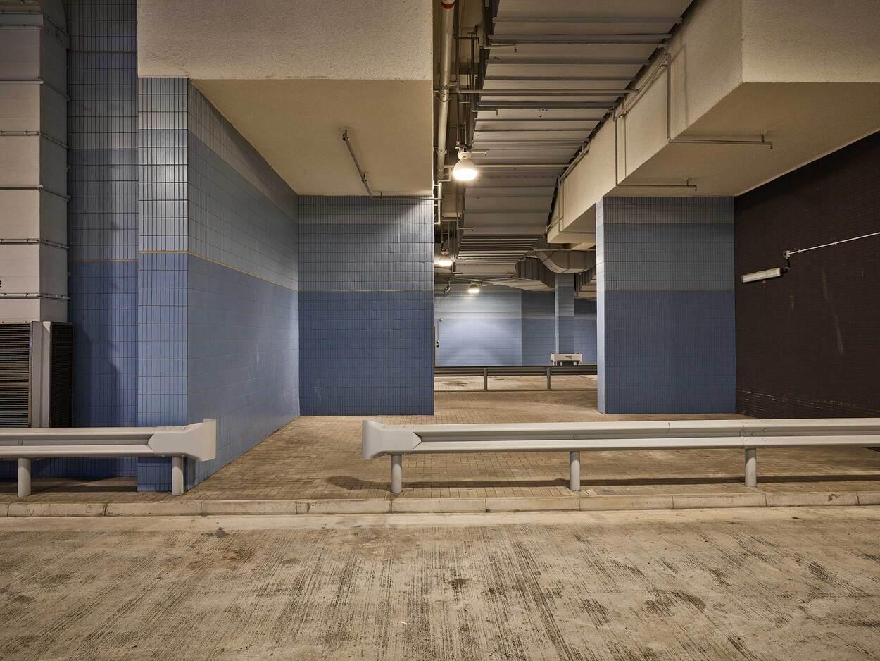 Interior view of an underground parking garage with concrete floor, columns and blue walls