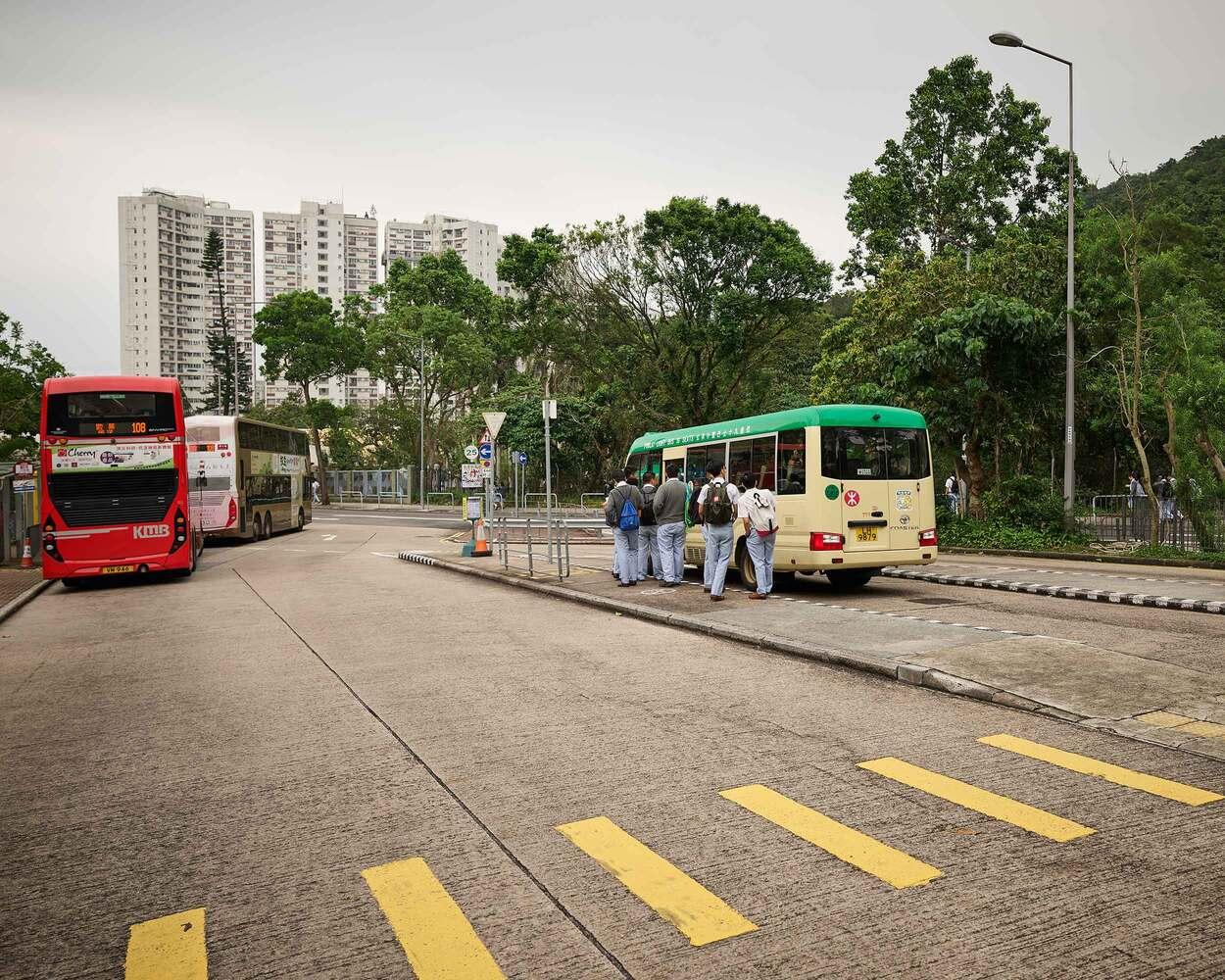 City street with buses parked near pedestrian crossing and buildings in background