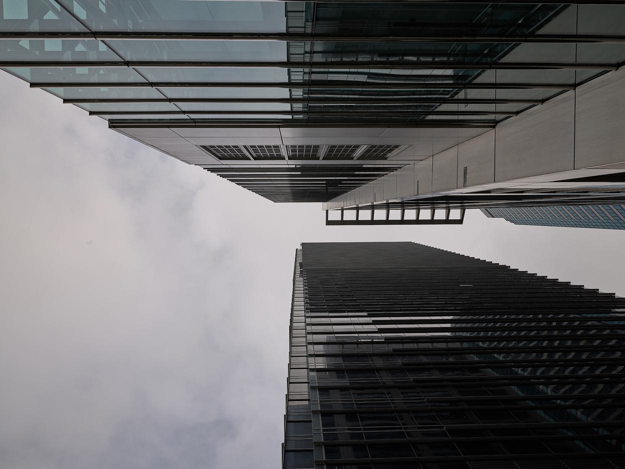 Upward view of modern skyscrapers with reflective glass facades against cloudy sky