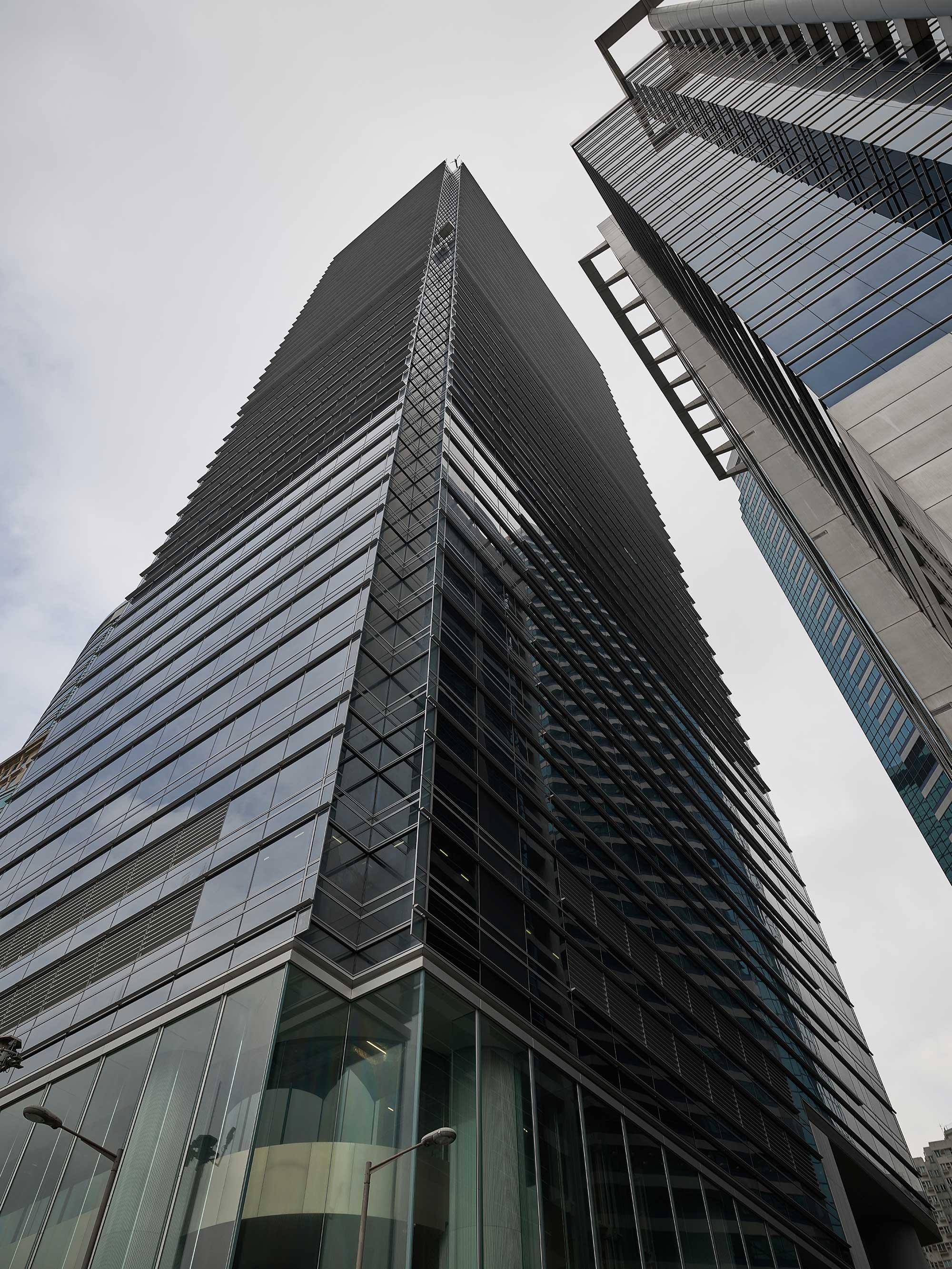 Upward view of a modern glass skyscraper on a cloudy day