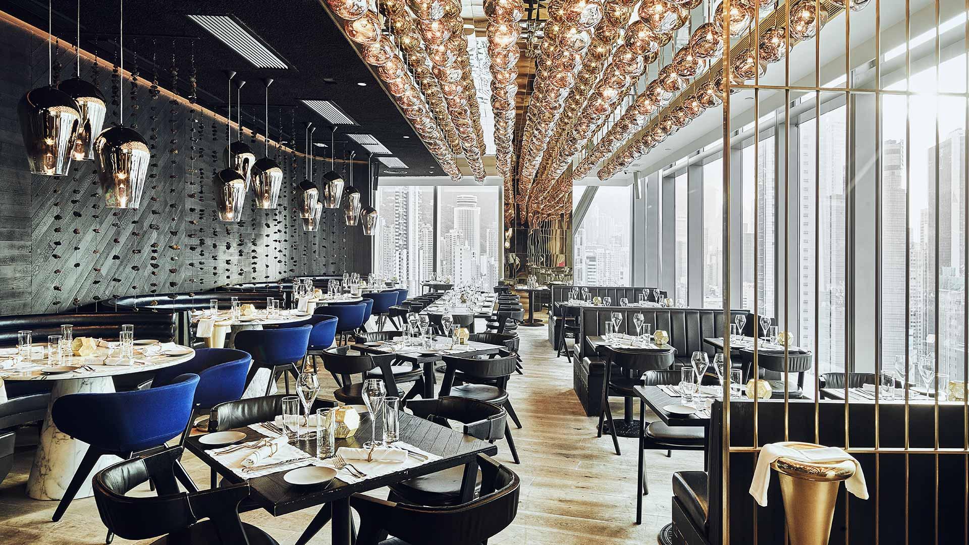 Modern restaurant interior with stylish ceiling lights, blue chairs and large windows