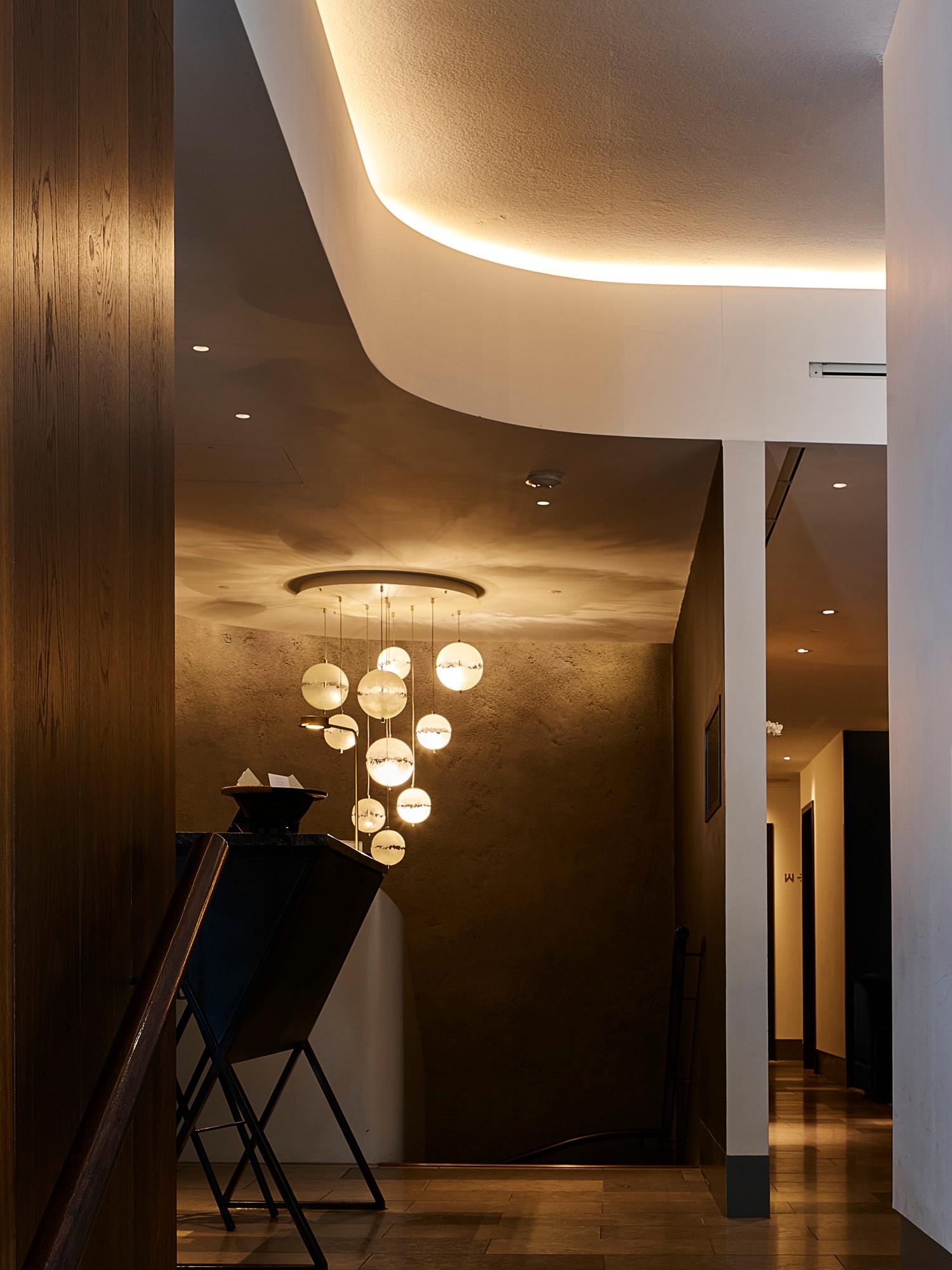 Curved Acosorb acoustic ceiling design with warm lighting in a hotel lobby