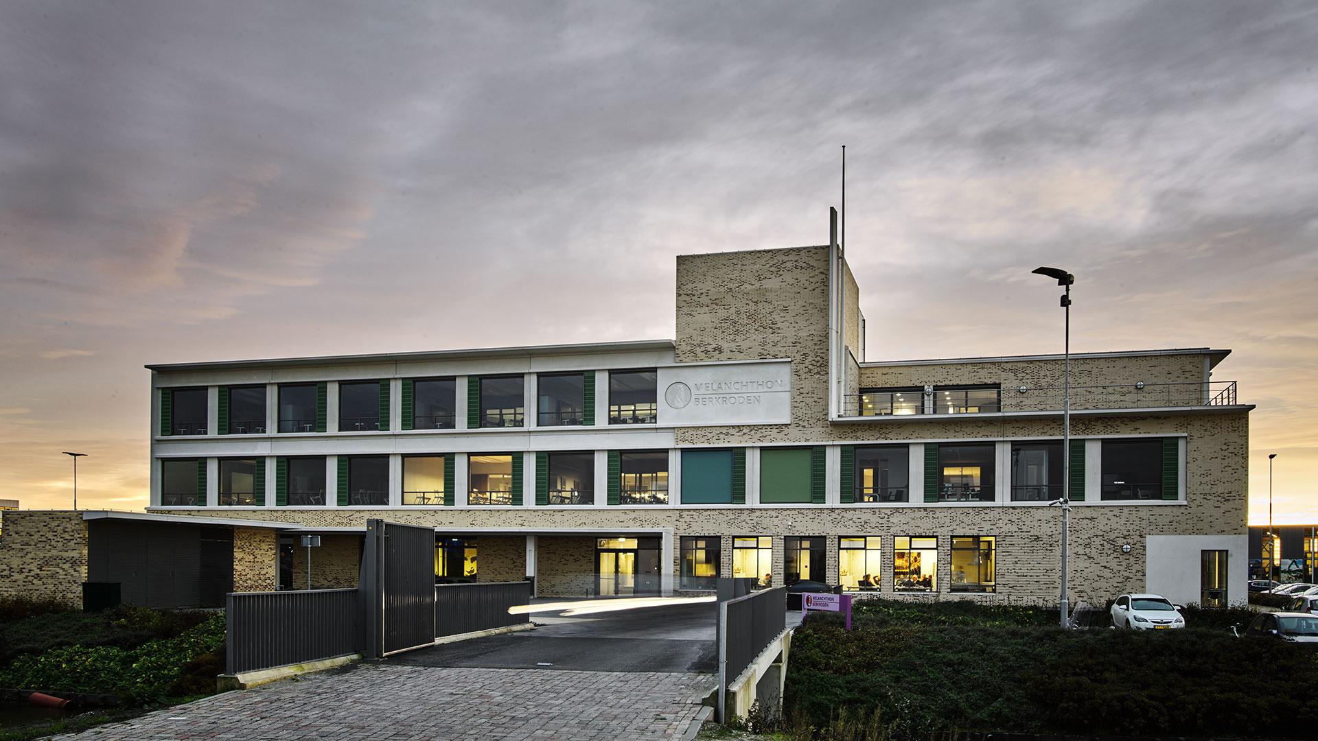 Modern exterior view of Melanchthon school building at sunset with landscaped entrance