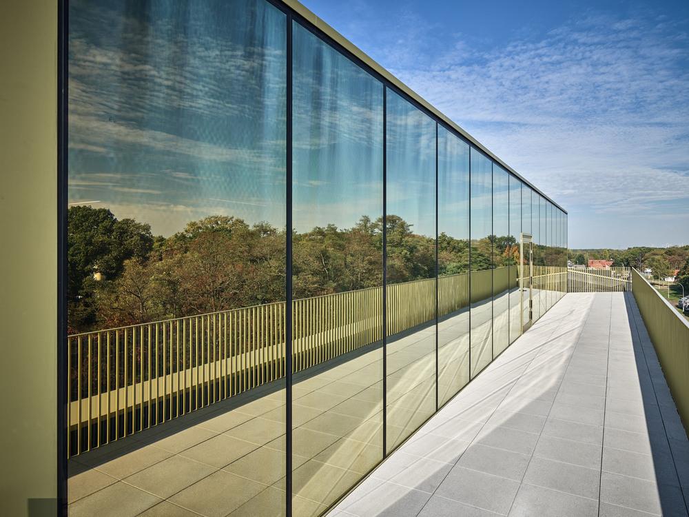 Glass facade of a modern building reflecting the landscape and blue sky